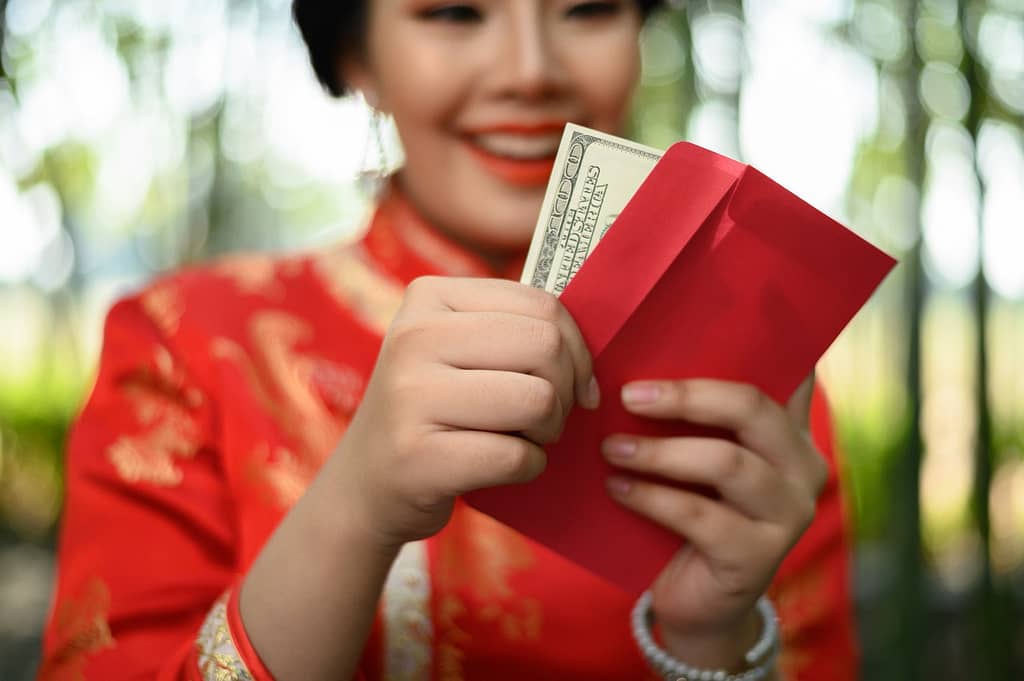 Isi Angpao Tidak Boleh Ganjil portrait pretty asian woman chinese cheongsam holding envelopes dollars